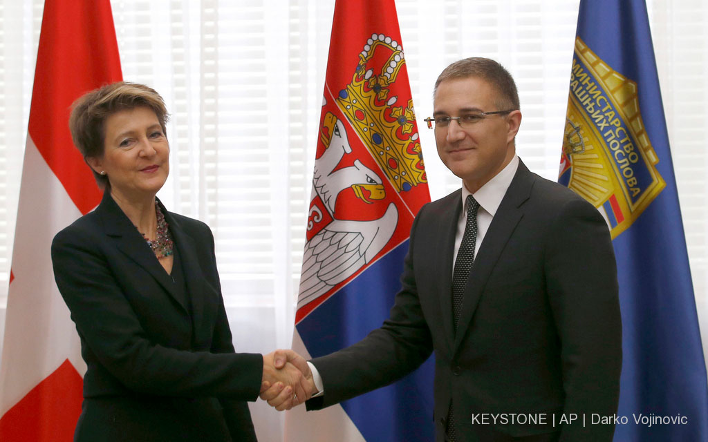 Il ministro serbo degli affari interni Nebojša Stefanović (a destra) accoglie con una stretta di mano la consigliera federale Simonetta Sommaruga. Sullo sfondo le bandiere della Svizzera e della Serbia.